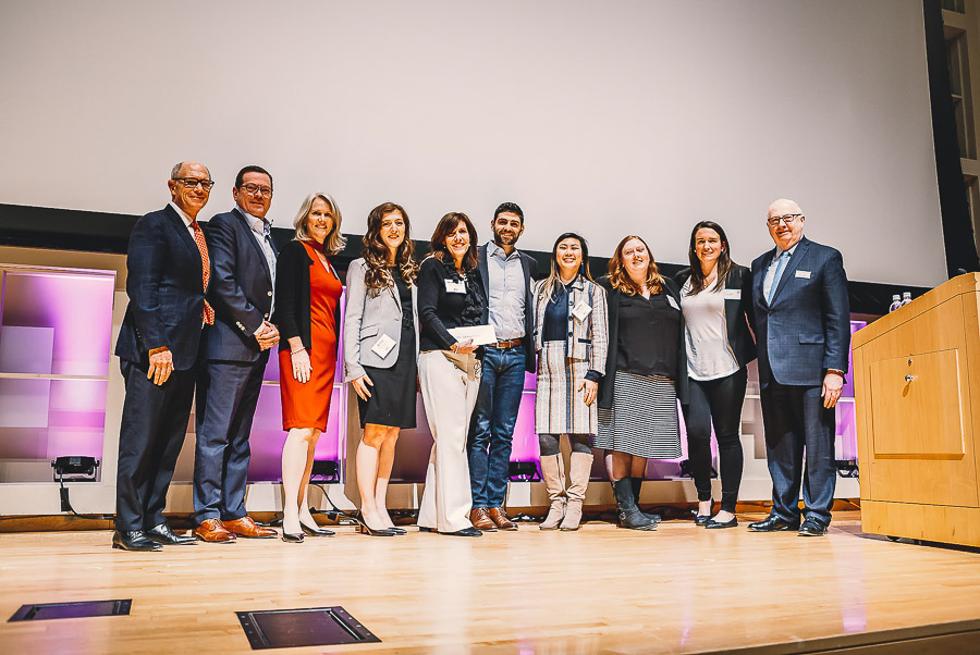 Photo of a group of students and Dean Walsh standing on stage