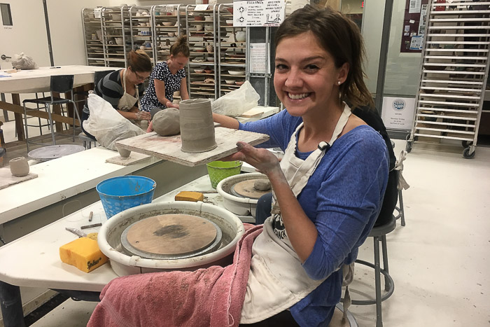 Photo of Emily at the clay studio holding up a project