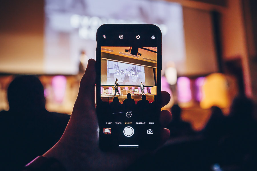 Photo of someone holding a phone and taking a photo of a presentation