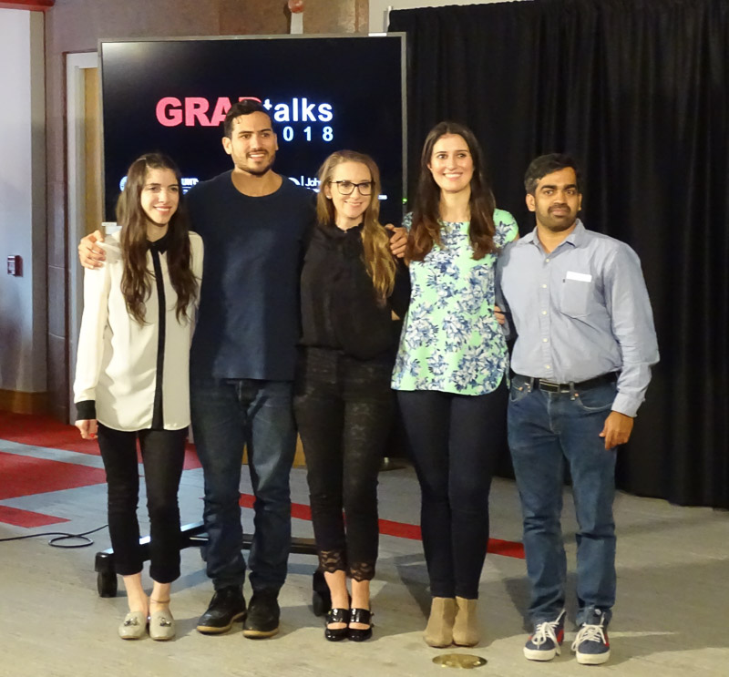 Photo of five of the six GRADtalks speakers standing in the front of the presentation room