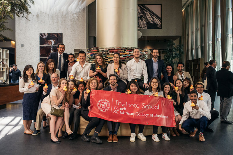 Photo of the MMH group holding a Hotel School banner