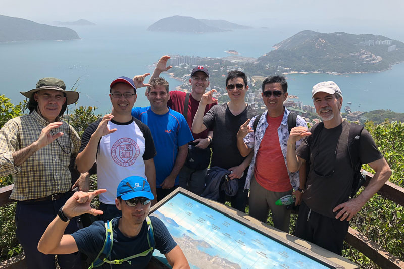 Photo of a group of people at the top of a hill with water in the background