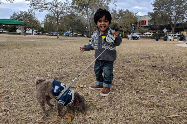 Photo of Karthika's son walking a dog and smiling