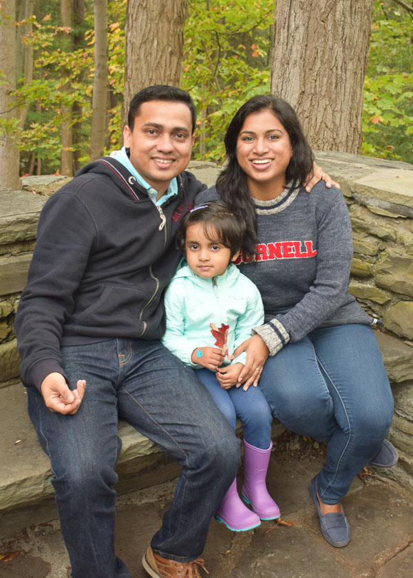 Photo of Amritha, her husband, and her daughter sitting outdoors