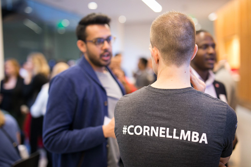 Photo of people talking wearing a #cornellmba shirt