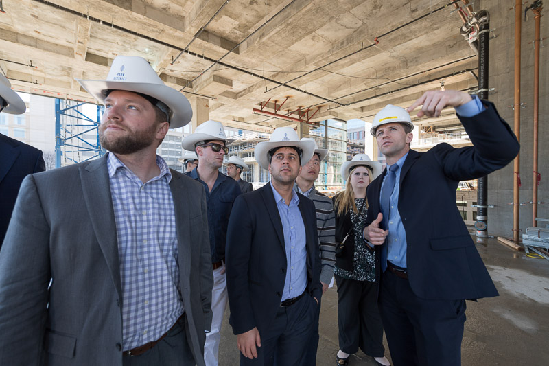 Photo of men wearing hard hats and cowboy hats at a construction site