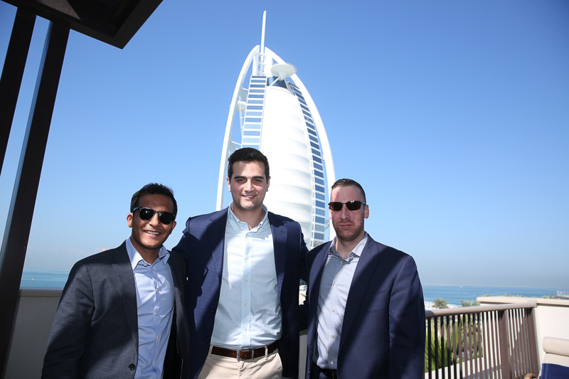 Photo of three men with a Dubai city building behind them