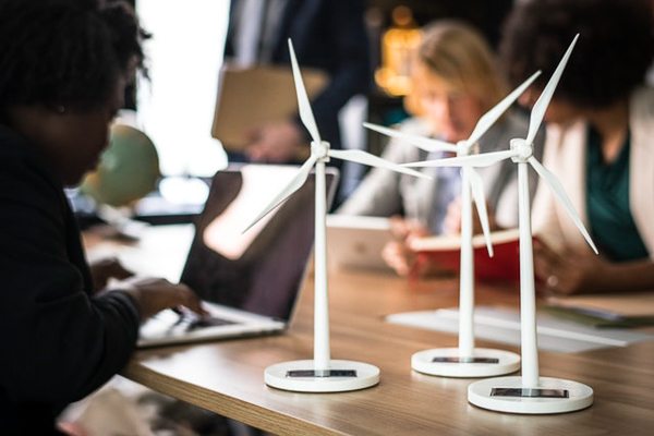 Photo of small model wind turbines on a desk with people working