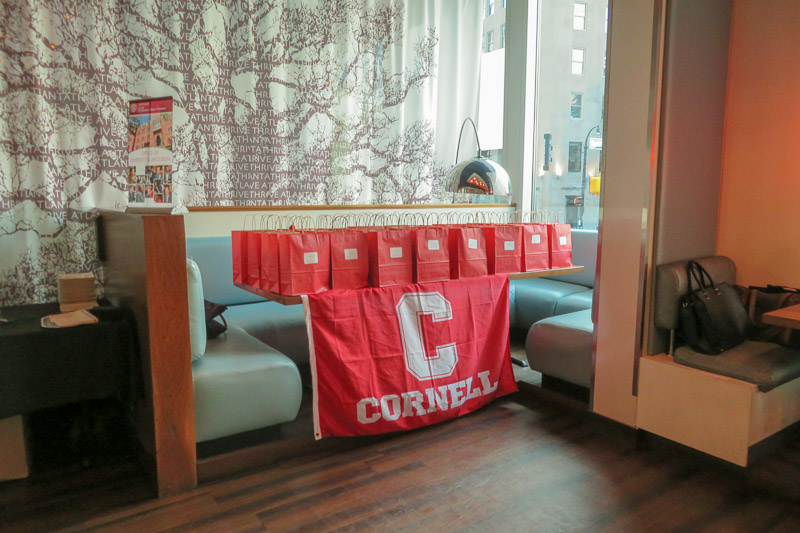 Photo of Cornell bags on a table with a Cornell banner