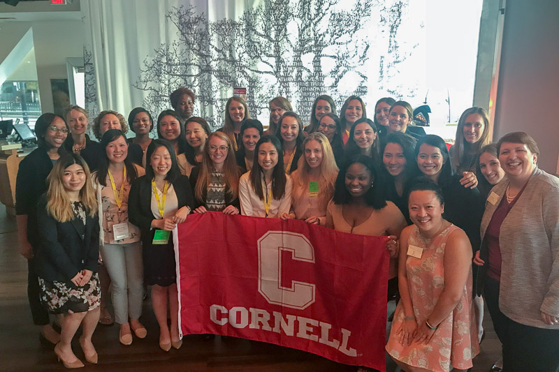 Photo of Cornell MBA women around a Cornell red banner