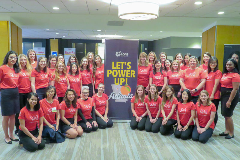 Photo of Cornell MBA women around a banner that says Let's Power Up!