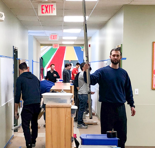 Photo of a man carrying a pole and others working