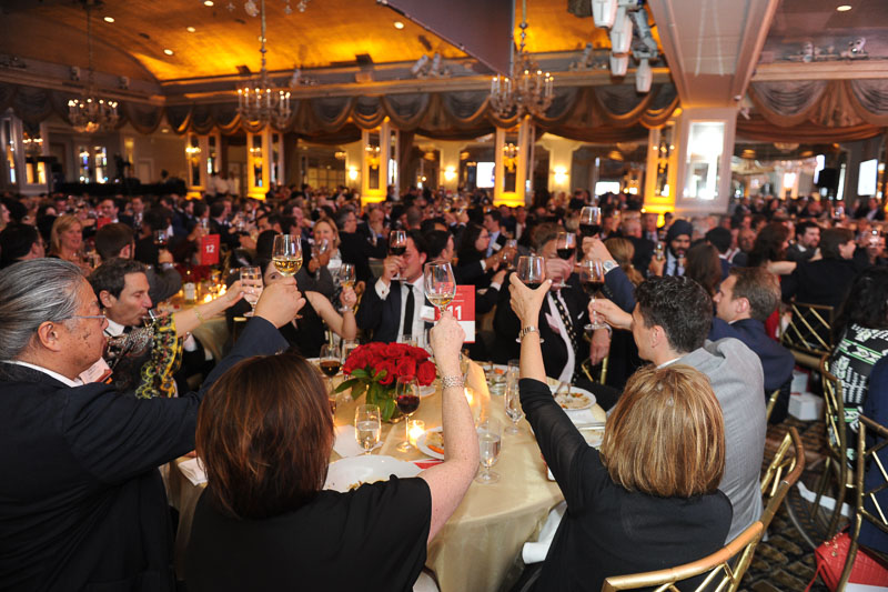 Photo of the people in the banquet hall raising their glasses for a toast