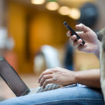 Photo of a person on a laptop and phone