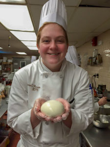 Photo of Lane holding a ball of dough and smiling