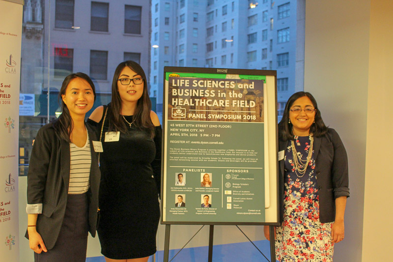 Photo of three women standing in front of the event sign