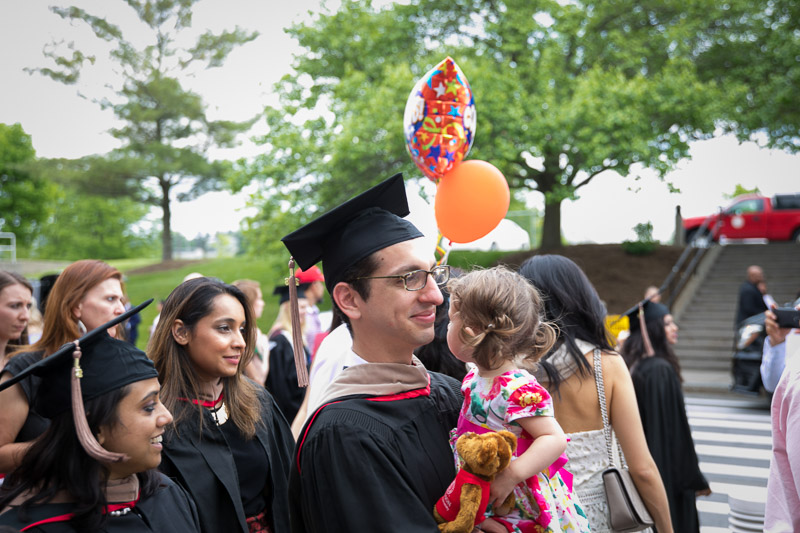 Photo of a graduate holding a child