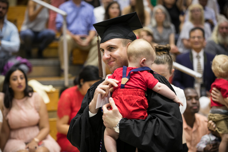Photo of a graduate holding a child