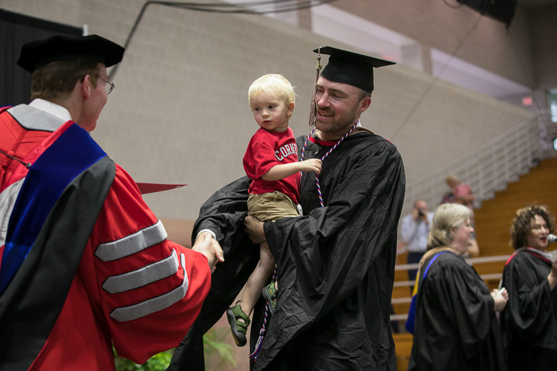 Photo of a graduate holding a child