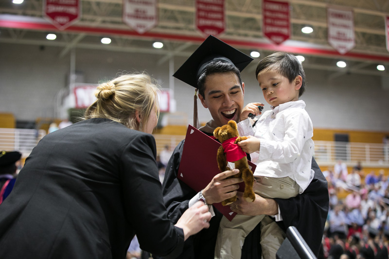 Photo of a graduate holding a child