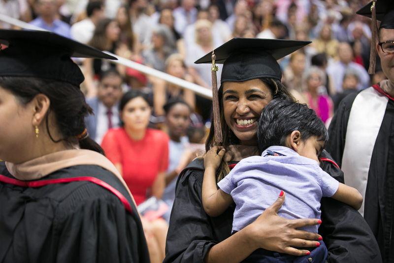 Photo of a graduate holding a child