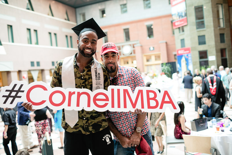 Photo of a graduate holding a #cornellmba sign