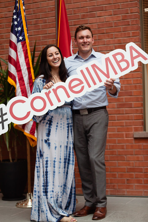 Photo of a man and women holding a #cornellmba sign