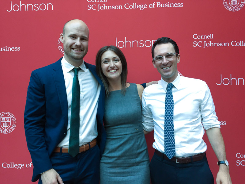 Photo of Sam, Christina, and Harrison in front of a Johnson backdrop