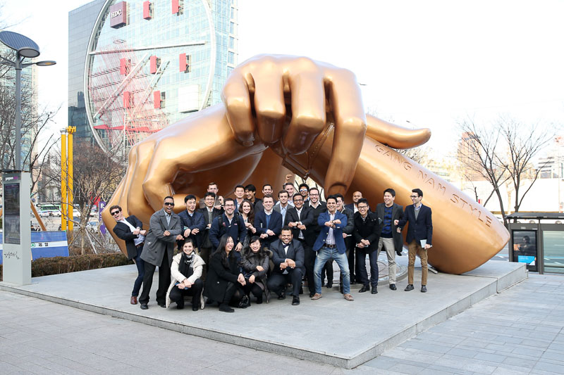 Photo of the group under an enormous statue of a hand on a plaza