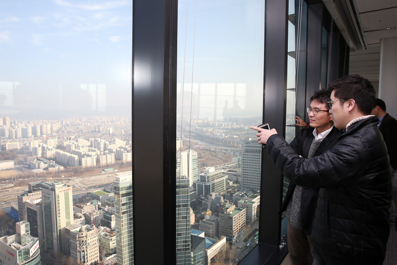 Photo of a man looking out a window and pointing from a high rise