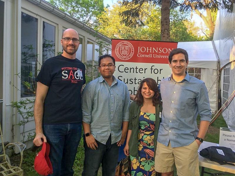 Photo of four people standing in front of an SGE banner