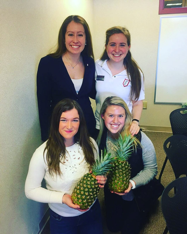 Photo of four ambassadors, two are holding pineapples