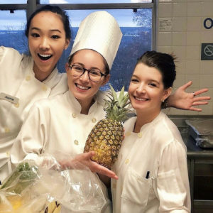 Photo of three students, one is holding a pineapple