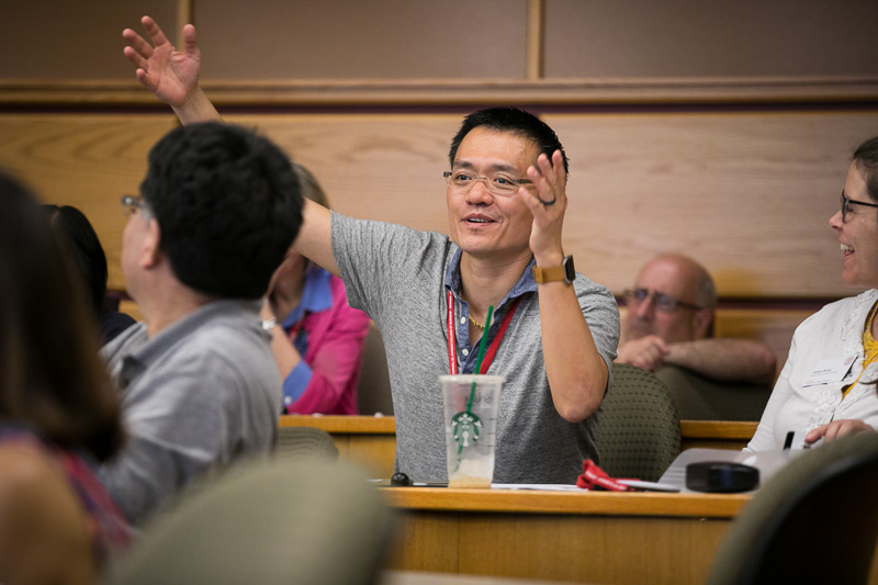 Photo of a man in the audience raising his hand