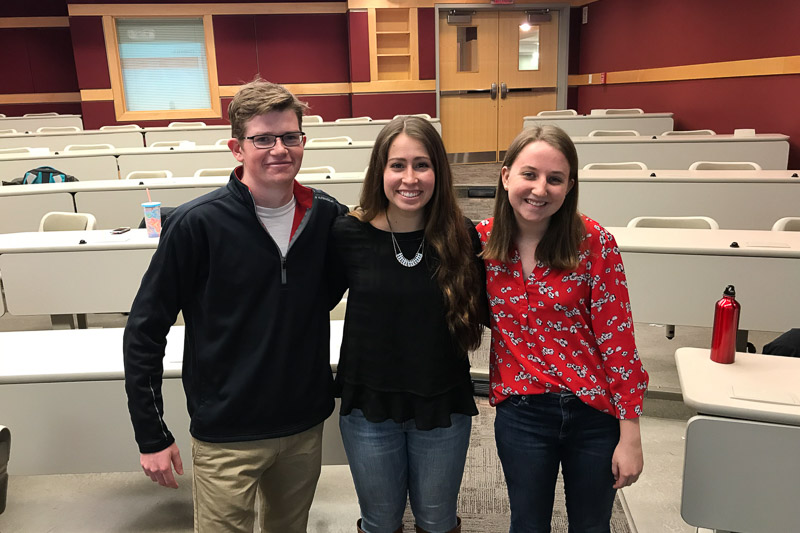 Photo of three people standing in a classroom