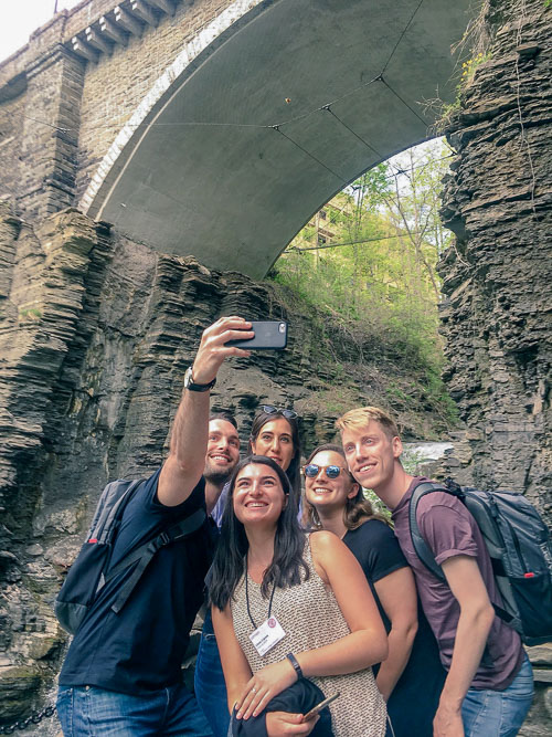 Photo of a group of 5 students taking a selfie with a waterfall behind them