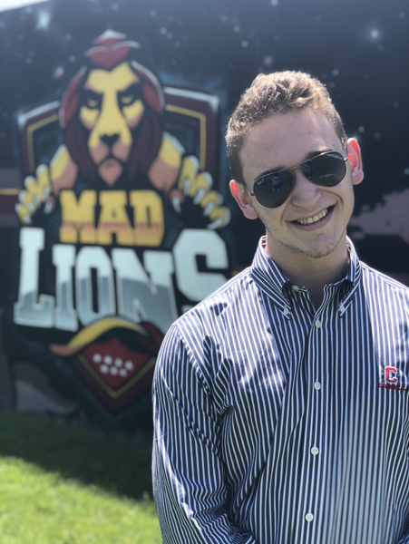 Joshua Greenspan in front of Mad Lions sign
