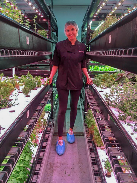 Photo of Sarah among an aisle of green plants