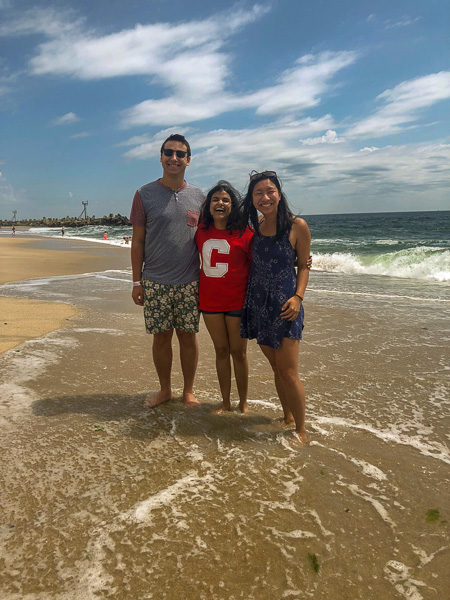 Photo of three students standing on the shore of the ocean
