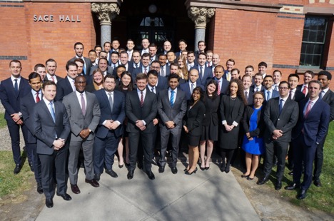 Photo of a large group of students dressed in business attire outside Sage Hall