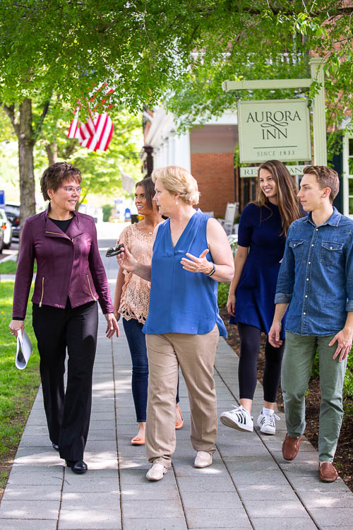 Photo of a group walking on the sidewalk in front of the Aurora Inn sign