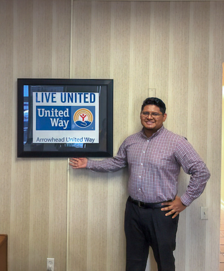 Photo of Julio standing in front of a digital display with the United Way logo