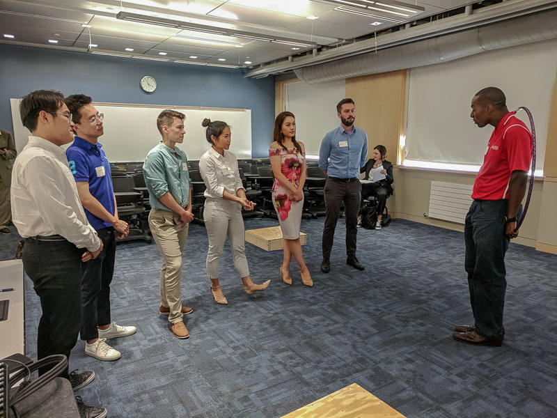 Photo of students standing and listening to a facilitator 