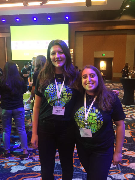 Photo of two students wearing name badges and standing among vendor displays