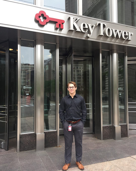 Photo of Noah standing at the entrance to Key Tower with revolving doors