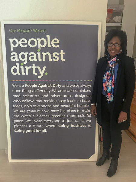 Photo of Lynn Wooten standing next to a sign at Method that says "People against dirty"