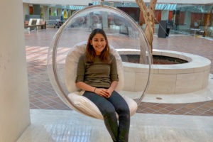 Photo of Sonal sitting in a circular swing in a lobby area