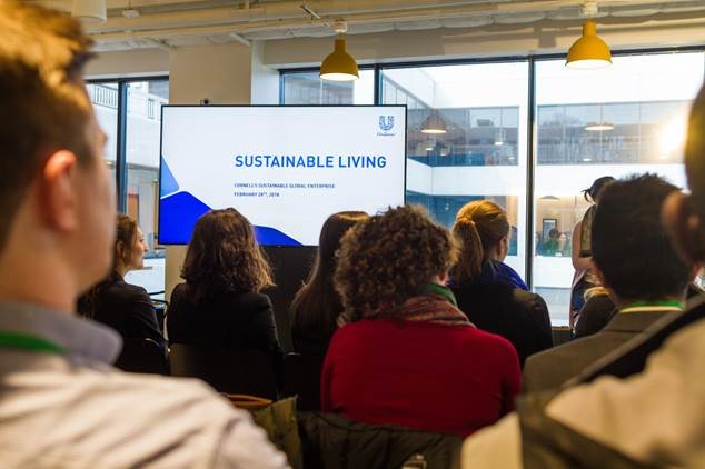 Photo of students listening to a presentation, slide says "sustainable living."