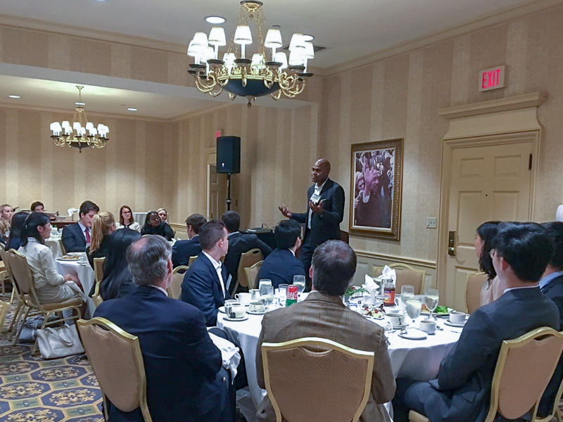 Photo of a man speaking at the front of a banquet room