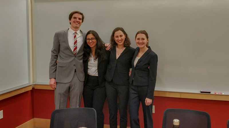 Photo of four students standing at the front of the classroom